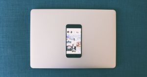 Dizüstü bilgisayarın üzerinde sosyal medya fotoğrafları açık akıllı telefon