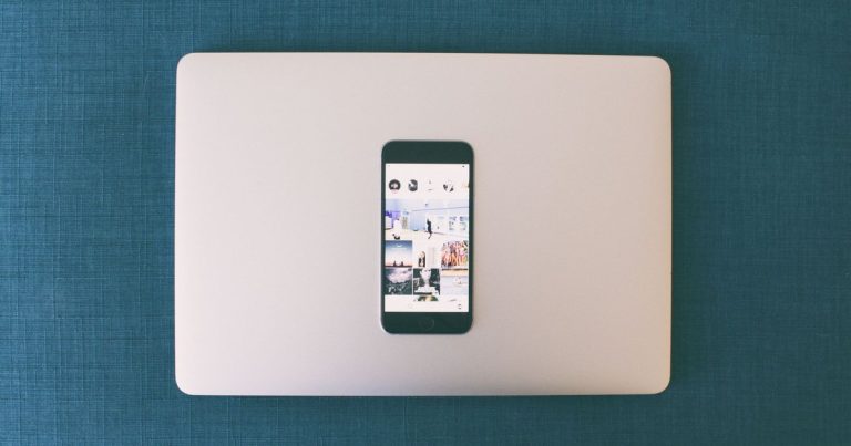 Dizüstü bilgisayarın üzerinde sosyal medya fotoğrafları açık akıllı telefon