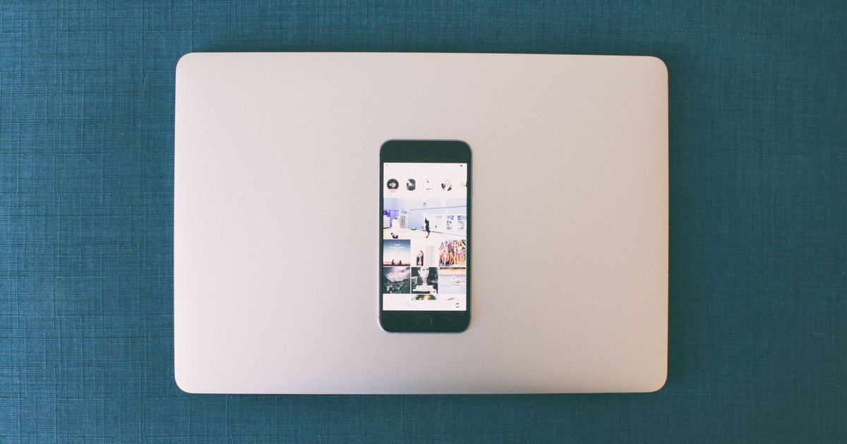 Dizüstü bilgisayarın üzerinde sosyal medya fotoğrafları açık akıllı telefon