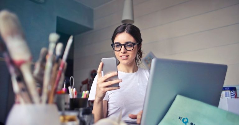 Yaratıcı çalışma alanında masada telefonunu kullanan kadın
