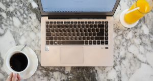 Mermer masada kahve ve portakal suyu yanında dizüstü bilgisayar, üstten görünüm