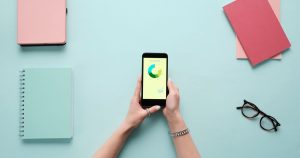 Mavi zeminde kırtasiye malzemeleriyle birlikte analiz ekranı açık akıllı telefon