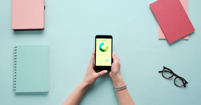 Mavi zeminde kırtasiye malzemeleriyle birlikte analiz ekranı açık akıllı telefon