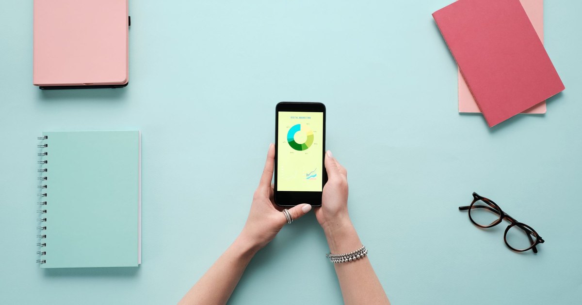Mavi zeminde kırtasiye malzemeleriyle birlikte analiz ekranı açık akıllı telefon