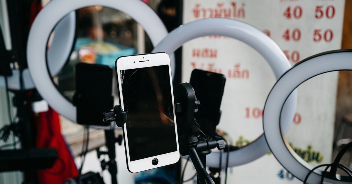 Halka ışıkların arasında tripoda takılı akıllı telefon
