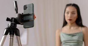 Tripoda takılı telefonun karşısında video çeken kadın