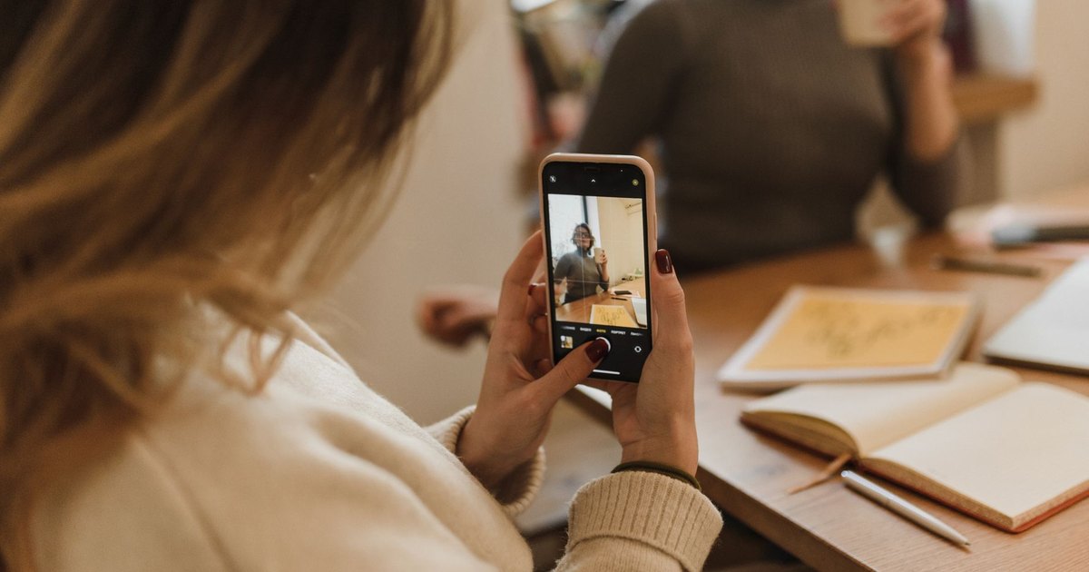 Ofiste telefonla fotoğraf çeken kadın
