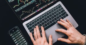 Telefon yanında grafik ekranı açık dizüstü bilgisayarda yazı yazan eller