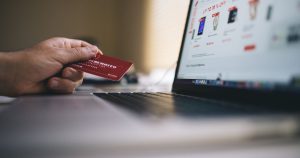 Kredi kartıyla dizüstü bilgisayardan online alışveriş yapan kişi