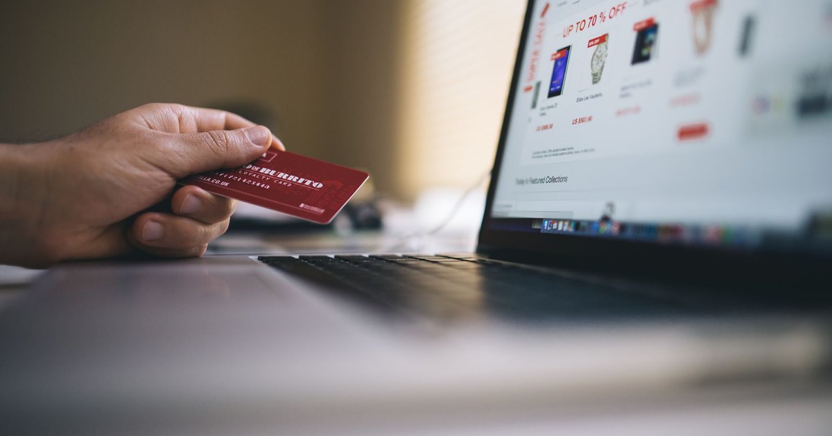 Kredi kartıyla dizüstü bilgisayardan online alışveriş yapan kişi