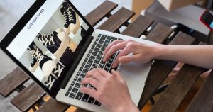 Dizüstü bilgisayarda online mağazanın ayakkabı ürün sayfasını inceleyen kullanıcı