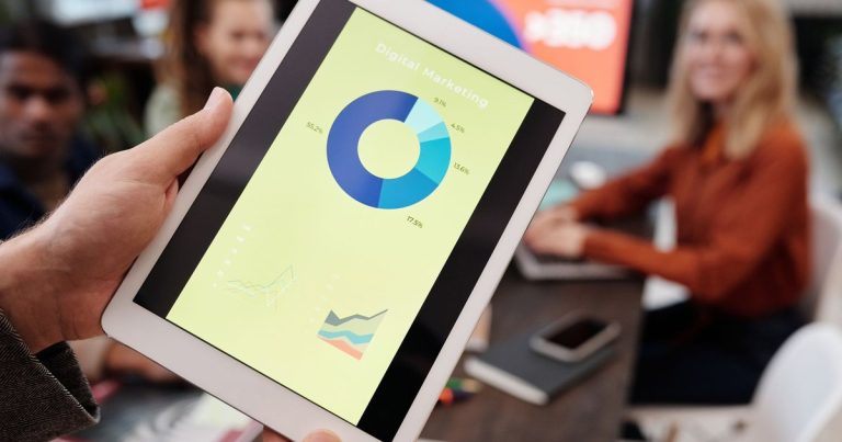 Toplantıda tablette dijital pazarlama istatistiklerini inceleyen ekip