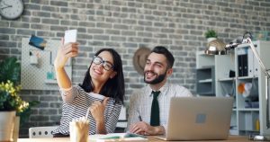 Çalışma alanında telefonla özçekim yapan güler yüzlü çalışma arkadaşları