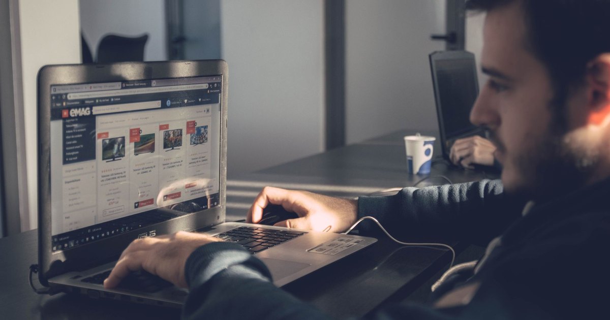 Modern ofiste dizüstü bilgisayarda online pazaryerine bakan adam