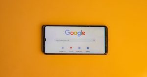 Sarı zemin üzerinde Google arama sayfası açık akıllı telefon