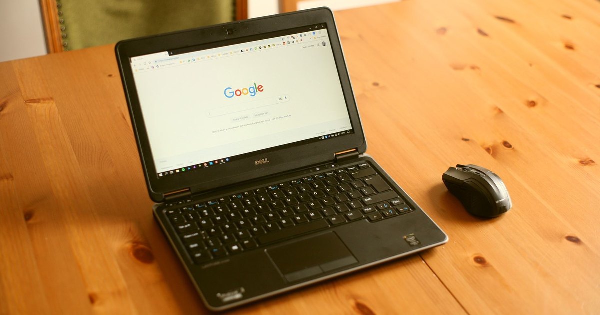 Ahşap masada Google ana sayfası açık siyah dizüstü bilgisayar ve fare