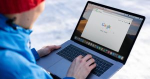 Dış mekânda dizüstü bilgisayarda Google'da arama yapan kişi