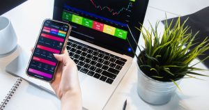 Dizüstü bilgisayar yanında telefonda grafik uygulaması kullanan kişi
