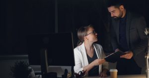 Loş ofiste geç saatte proje konuşan iki çalışma arkadaşı