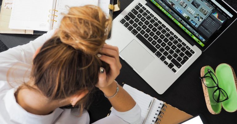 Dizüstü bilgisayar, telefon ve defterlerle çalışırken stresli görünen kadın, üstten görünüm