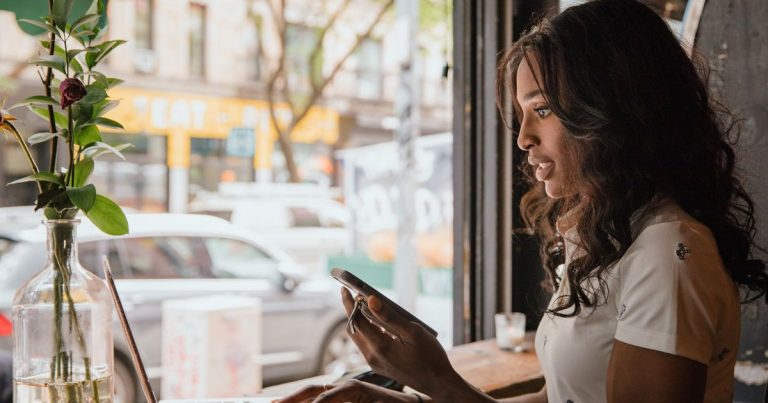 Kafede dizüstü bilgisayar ve telefonla çalışan kadın