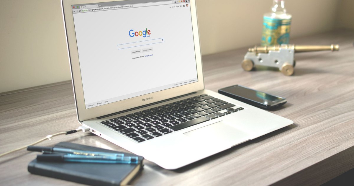Masada Google arama sayfası açık dizüstü bilgisayar ve yanında akıllı telefon