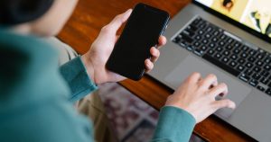 Telefon ve dizüstü bilgisayarla sosyal medya hesaplarını yöneten kişi