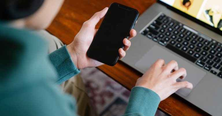 Telefon ve dizüstü bilgisayarla sosyal medya hesaplarını yöneten kişi