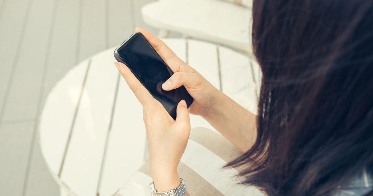 Güneşli bir günde dışarıda telefonunu kullanan kadın